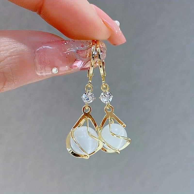 Boucles d'oreilles pendantes dorées aux reflets d'opale blanche